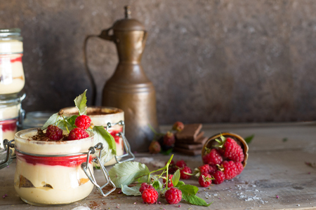 Tiramisu cake in glass jar with red raspberry, dark still lifeの写真素材