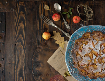 Wild bright apples and sweet apple cake over old style wooden tableの写真素材