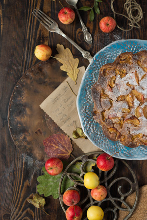Wild bright apples and sweet apple cake over old style wooden tableの写真素材