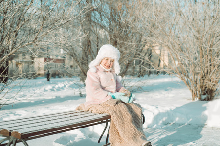 Little girl with Christmas toy sitting outside in the park, with smile on face, joyful childの写真素材