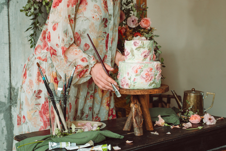 Tea time, Beautiful woman hands with tea pot, beautiful flower bouquet, cake, arranged on tableの写真素材