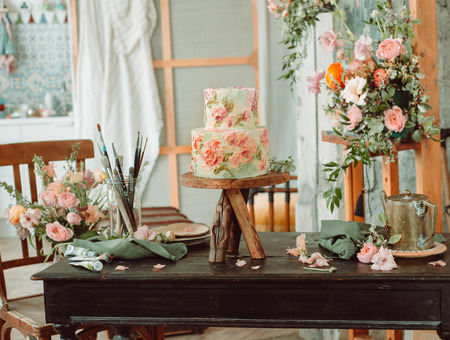 Cake on wooden stand with flowers and tubes of paint tubes, beautiful vintage roomの写真素材