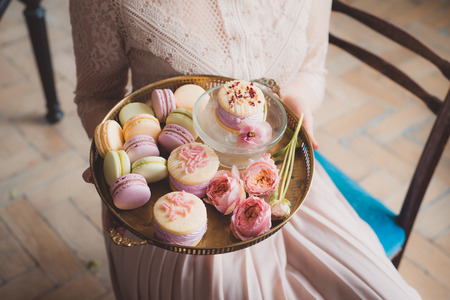 macaroon, Variety desserts of light colors on metal plate in woman handsの写真素材