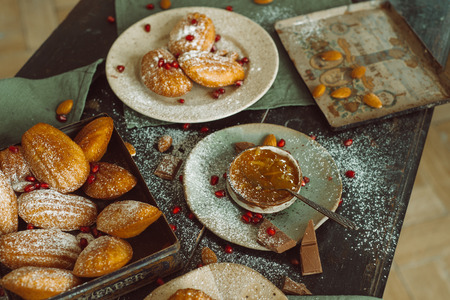 Cookies with jar of jam, chocolate, almonds and pomegranate on table, top viewの写真素材