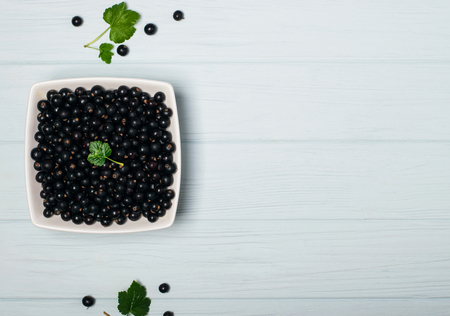 Black currant on wooden table with leaf sprigの写真素材