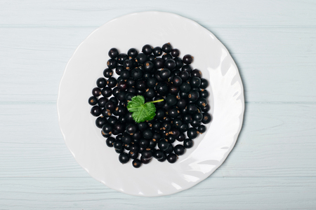 Black currant on wooden table with leaf sprigの写真素材