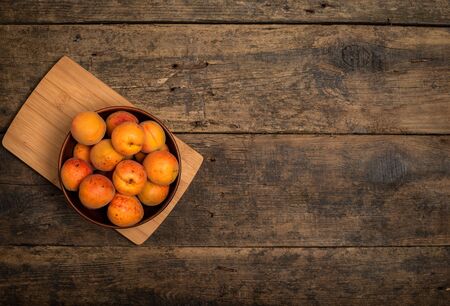 Delicious ripe apricots in a wooden bowl on the table close-up. Horizontal view from aboveの写真素材