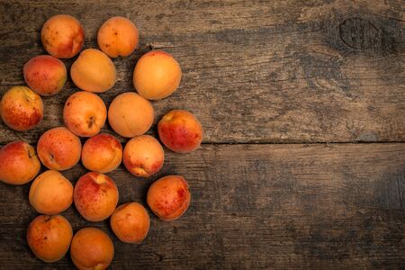 Delicious ripe apricots in a wooden bowl on the table close-up. Horizontal view from aboveの写真素材