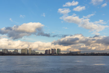 Urban winter landscape from frozen lake. Waste processing plant behind lakeの写真素材