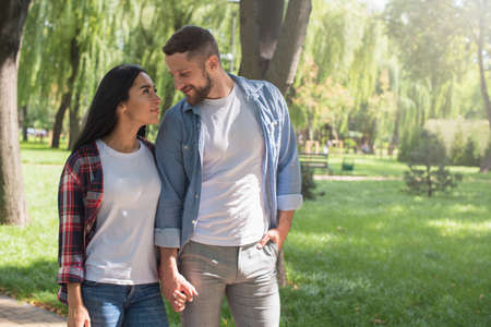 Love sight. Couple on date holding hands. Handsome man and pretty girl on a date. Couple in love walking and resting in the park.の写真素材