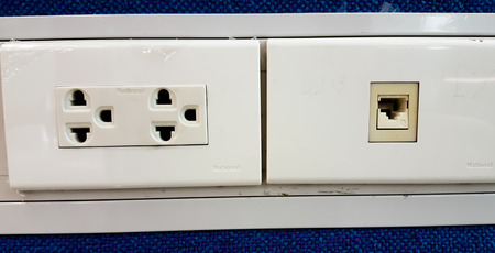 a white plug socket on the blue wall