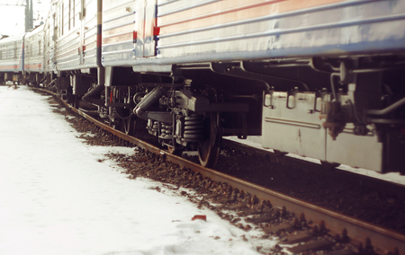 Wagon train, standing on the rails, which are covered with rust. There is snow around the train.