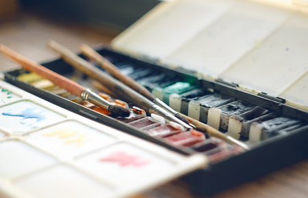 Folding box with watercolor paints in cuvettes and brushes of squirrel hair, as well as a plastic form used as a paletteの写真素材