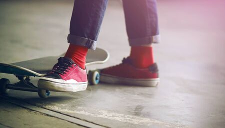 The guy in jeans, red socks and pink sneakers stands near his skate and moves his leg to ride on now.の写真素材