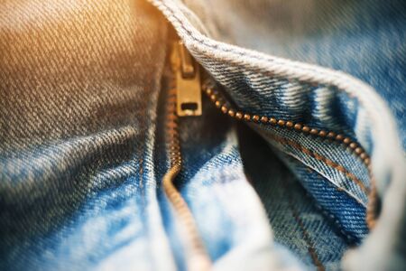 Zipper-clasp made of brass on blue trendy worn unbuttoned jeans, which are part of the youth style.の写真素材