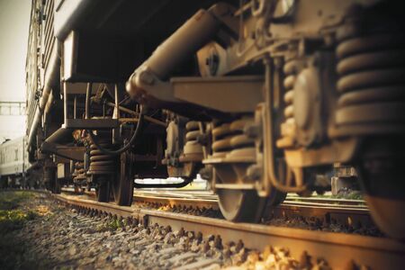 A view from below of the rusty old wheels of a heavy electric train standing on the tracks on a...