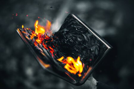 A black-and-white image of a man holding an old book in his hand, which is burning with a bright red flame.の写真素材