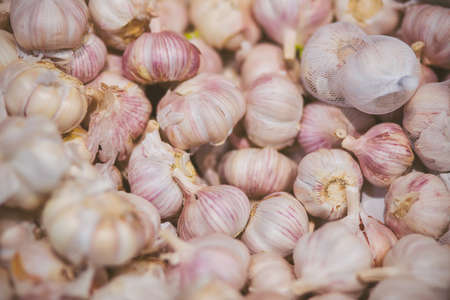 In the grocery store, there are many heads of ripe, fragrant garlic in the husk. Ingredient for cooking. Rich harvest.の写真素材