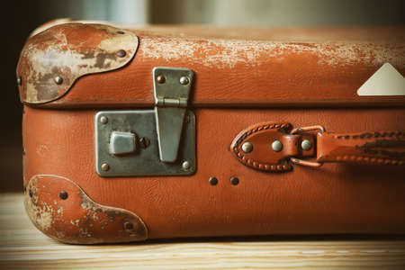 An old brown suitcase with an elegant handle, worn with time, which lies on a wooden bench at the station. Journey.の写真素材
