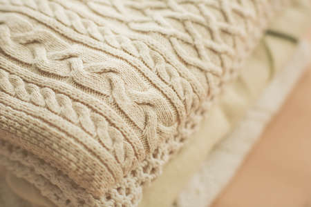 Warm light wool sweaters with different patterns are stacked in a neat pile. The view from the top....