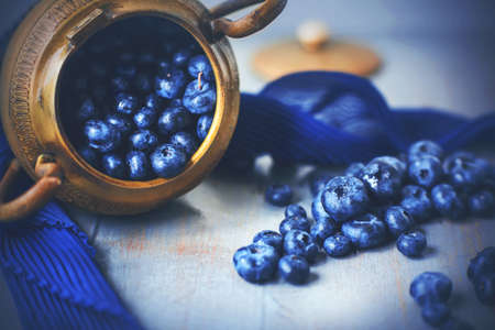 An old golden Greek bowl fell on its side on the table and spilled out the ripe blue berries of...