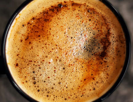 A close-up top view of a black mug of hot, aromatic coffee with cinnamon, which is well invigorated in the early morning.の写真素材