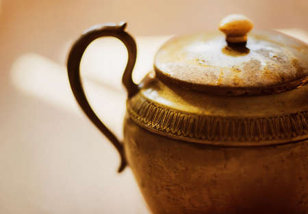 The antique copper elegant beautiful teapot is illuminated by a bright warm light. Genie's magic lamp. Asian old gold pot.の写真素材