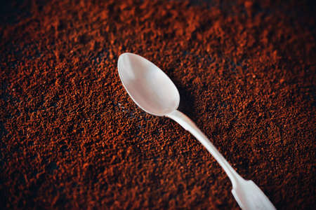 An elegant silver teaspoon lies on the fragrant ground coffee. Instant invigorating coffee in the morning. Love of coffee.の写真素材