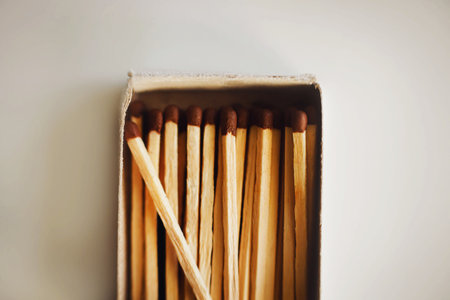 In an open cardboard matchbox lying on a white table, there are wooden matches illuminated by light. Flammable objects. Household items.の写真素材