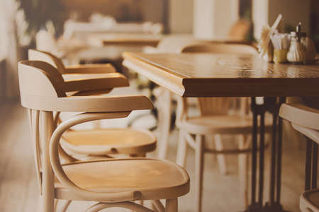 An empty hall with no visitors in the cafe. Beautiful wooden tables and chairs. Cafe interior. Closing restaurants during the crisis and pandemic.の写真素材