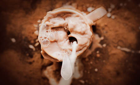 The human sloppily poured milk into a mug with warm cocoa. Mess in the kitchen. An invigorating drink for breakfast. Coffee with milk.の写真素材