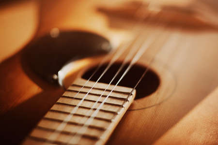 An old vintage acoustic guitar with metal strings is illuminated by sunlight. A musical instrument....