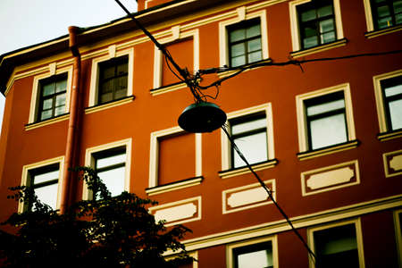 A view from below of the facade of an old vintage red building and an unlit street lamp. A house in the European capital. tourism and travel.の写真素材