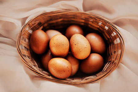Beautiful chicken brown Easter eggs lie in a wooden wicker basket for Easter. Food for religious holidays.の写真素材