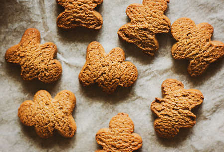 Top view of fresh homemade oatmeal cookies in the form of gingerbread men lying on baking paper. home cooking. sweet food.の写真素材