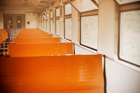 The interior of an old empty retro train car with orange seats on a bright day. Blurred background inside the train. Traveling alone.の写真素材
