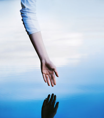 The hand of a woman in a white turtleneck stretches in the clear water of the lake, leaving circles...