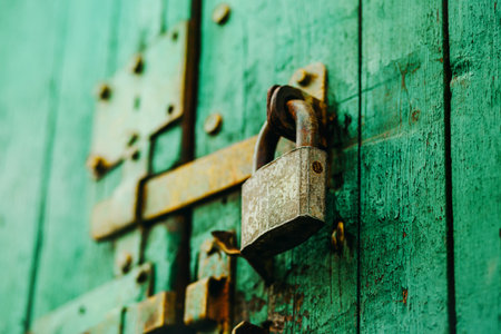 An old vintage metal padlock closes the wooden painted gate with a latch. closed.の写真素材