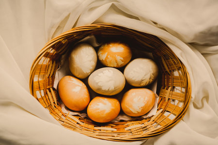 Beautiful chicken eggs are decorated with Easter drawings and lie in a wooden wicker basket. Religious holiday and food.の写真素材
