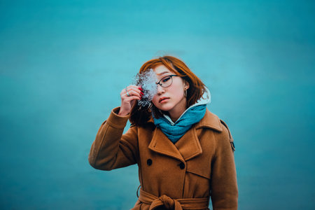 Portrait of a beautiful young red-haired Asian woman holding a transparent piece of ice in her hand, standing against the background of a frozen sea in winter. North.の写真素材
