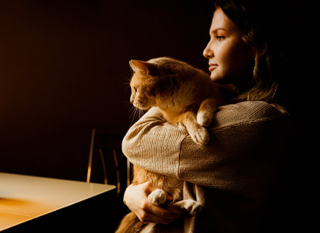 Portrait of a beautiful young woman in home clothes with a ginger fluffy cat in her hands. Home comfort with your favorite pet.の写真素材