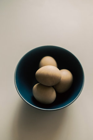 On a plain background there is a blue bowl with eggs dyed with natural dye for the Easter holiday. minimalism.の写真素材