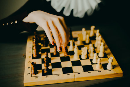 A woman in an ancient queen's robe holds a chess piece in her hand, thinking about the next move in the chess game. sport. A logic game.の写真素材