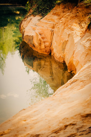 A stunning landscape photo captures the beauty of steep sandy shores, a forest, and a crystal-clear river reflecting it all on a sunny summer day. Nature, adventure, ecology and the serenity.の写真素材