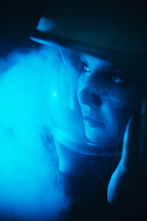 A beautiful young woman in a space helmet, adorned with star-studded makeup, amidst the vastness of space and mysterious cosmic fog. Human imagination and desire to journey into the unknown.の写真素材