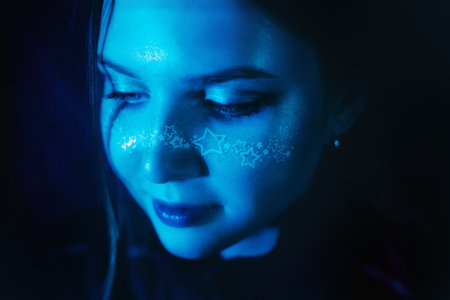 In the depths of a nightclub, a stunning young woman with makeup adorned with stars radiates a...
