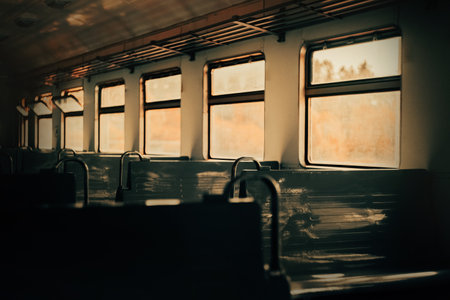 The empty interior of an electric train car, illuminated by rays of sunlight streaming in through the windows during sunset. It portrays a journey on public transportation. Solitude.の写真素材