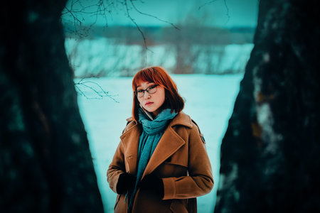 A portrait of a young, beautiful woman on a cold winter's day in a park among trees. It illustrates a refreshing outdoor walk in January.の写真素材
