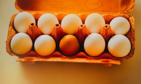 There is an orange package of chicken eggs on a white table, illuminated by sunlight. Eggs from the store. A protein product. Easter.の写真素材