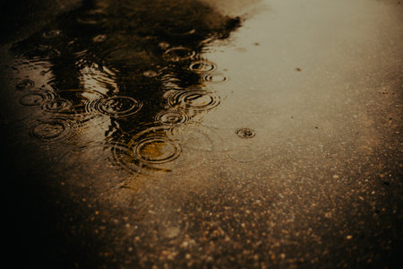 On a dark and rainy evening, the raindrops fell into a puddle in the city streets. The weather was bad.の写真素材